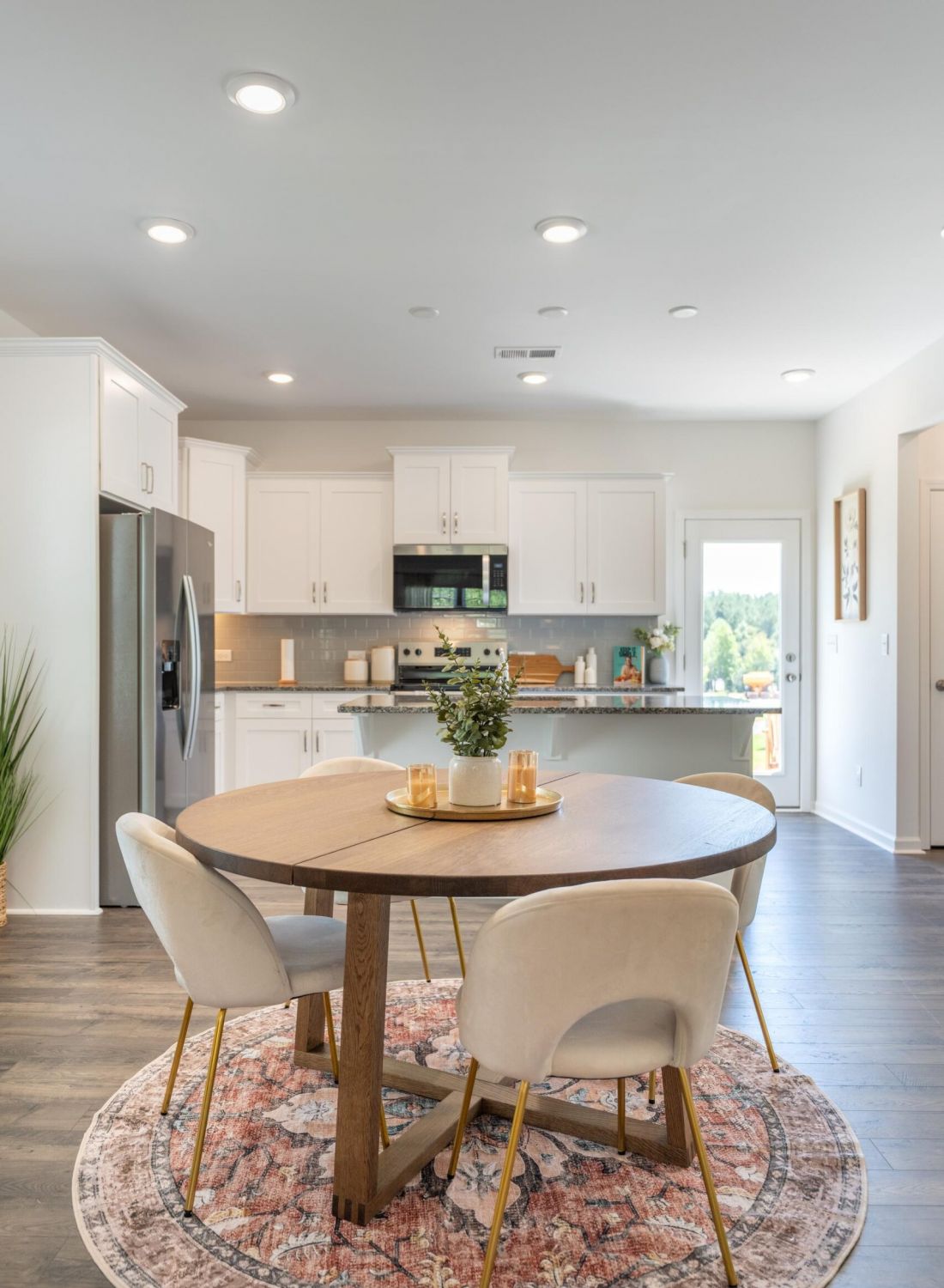 The Bend at Cramerton Mills modern kitchen and dining area with round table, four chairs, and white cabinets in a bright, open space.
