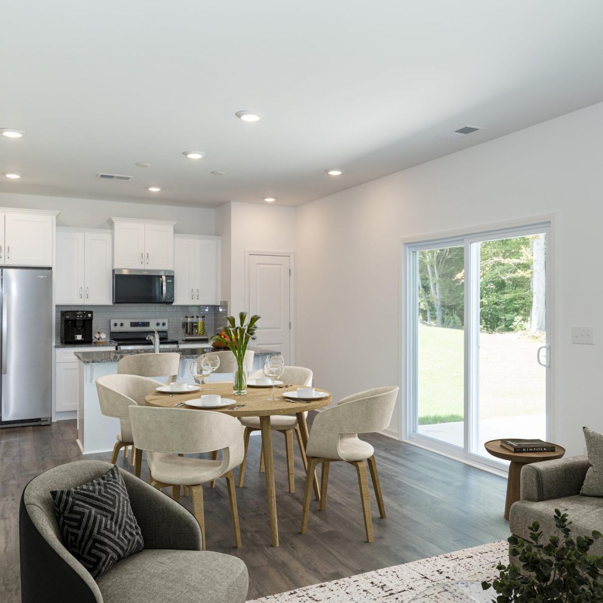 The Bend at Cramerton Mills modern open-plan kitchen and dining area with white cabinets, round table, and large glass doors to outside.