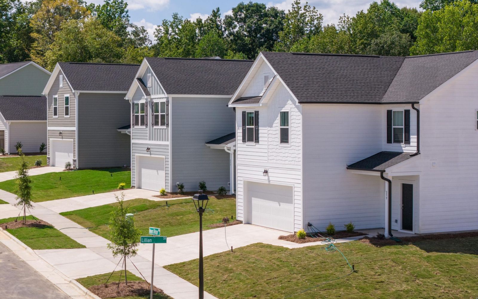 The Bend at Cramerton Mills row of modern suburban houses with garages and lawns on a sunny day.
