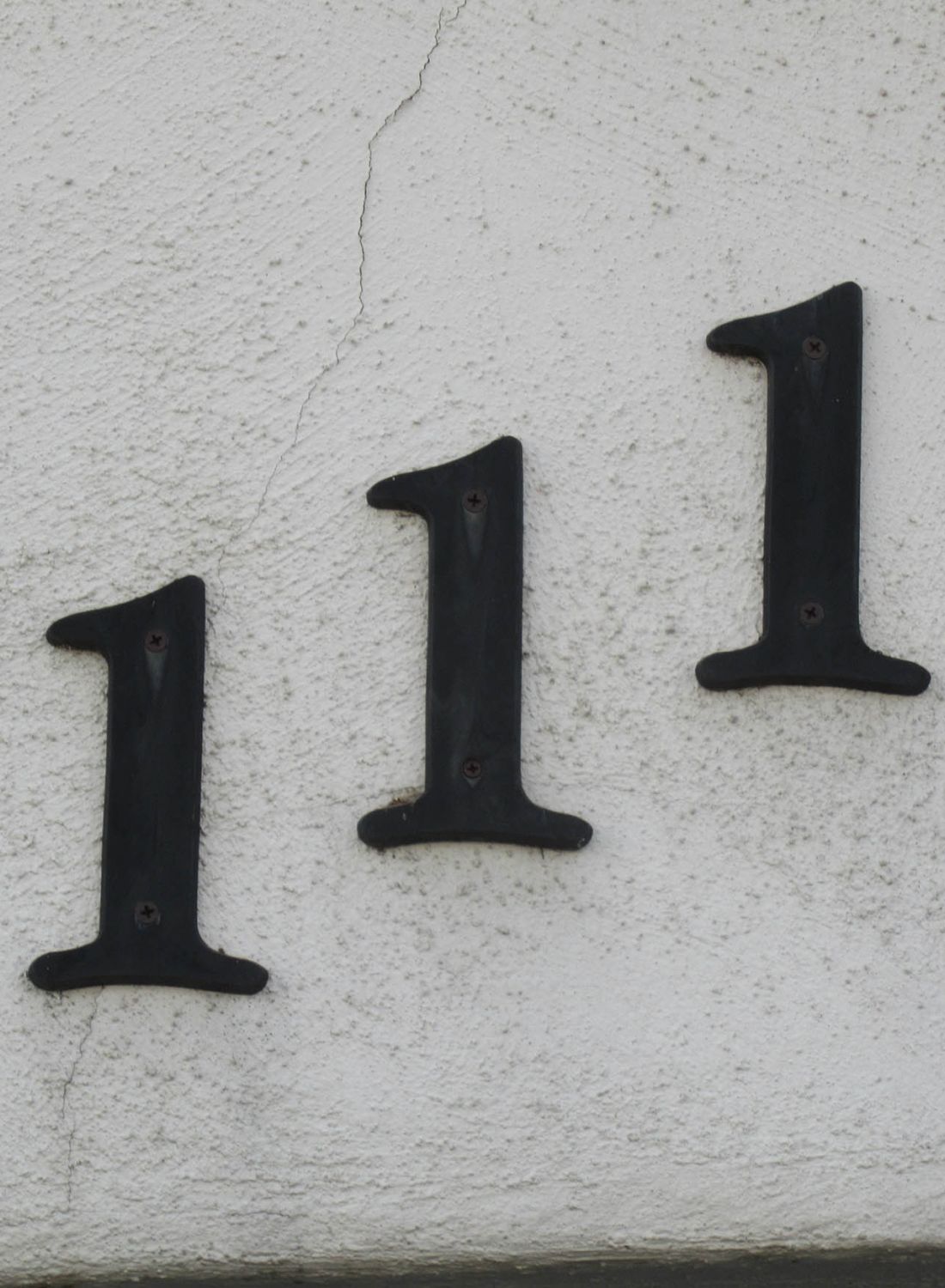 Black iron house numbers on white stucco